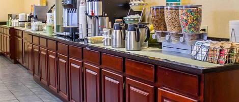 A hotel breakfast bar with coffee machines, cereal dispensers, and a "Healthy" sign.