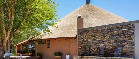 A building with a thatched roof, stone wall, and potted plants.