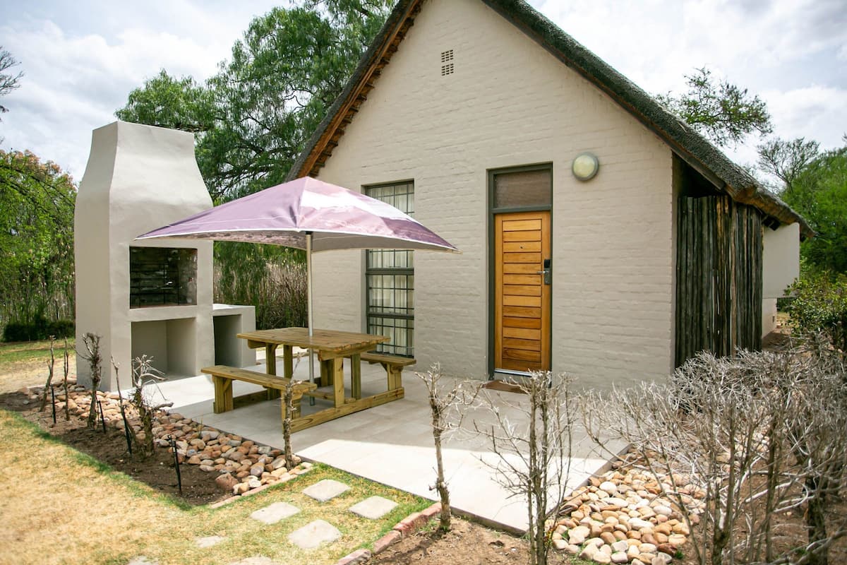 Ein Haus mit einer Terrasse, einer Holztür und einem gepflasterten Weg.