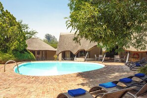 Una piscina al aire libre, sombrillas, tumbonas