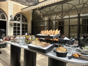A buffet setup with various breads, jars of spreads, and a person in the background.