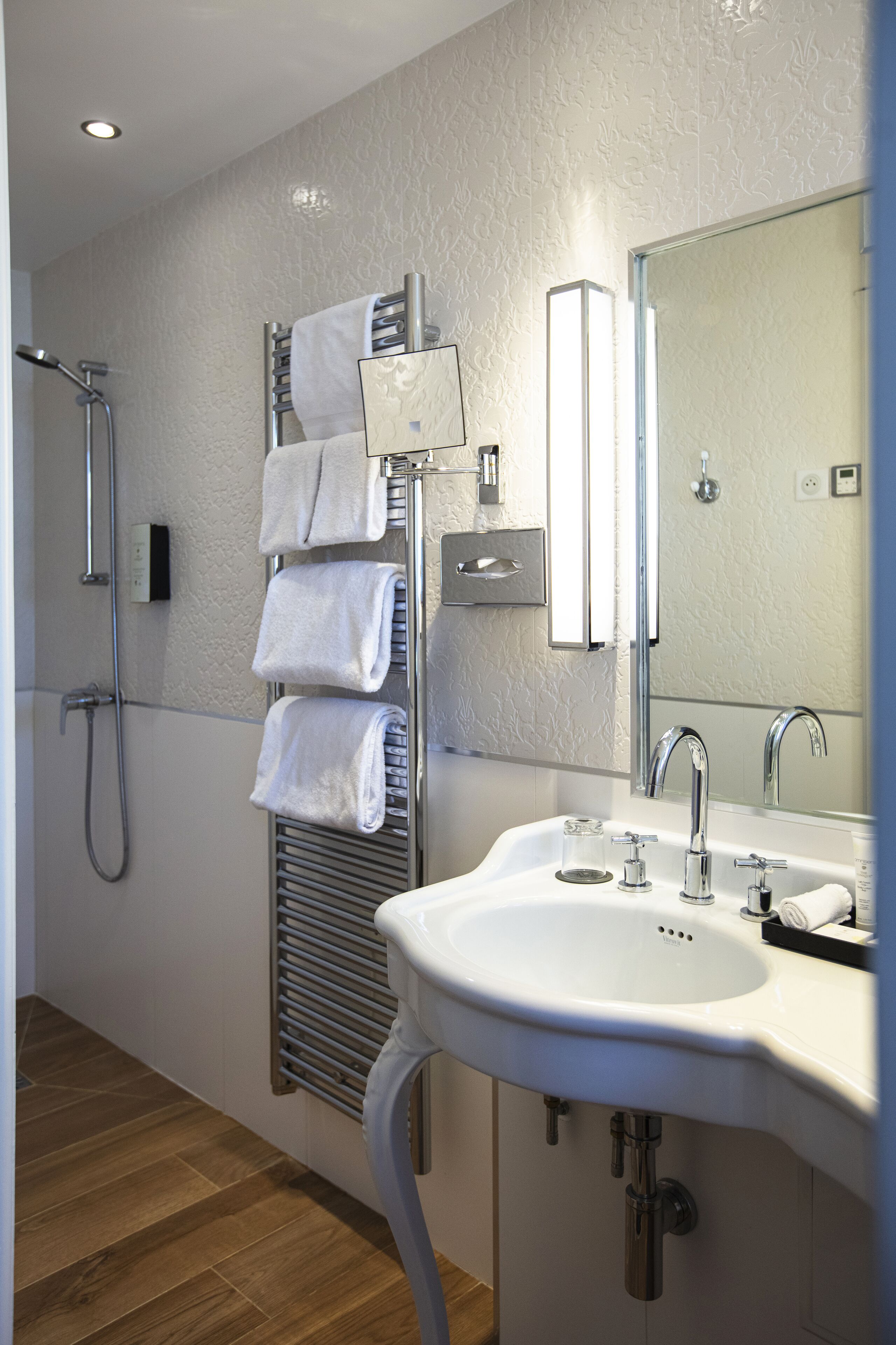 Un baño moderno con ducha, toallero, lavabo y espejo.