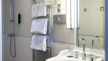 Un baño moderno con ducha, toallero, lavabo y espejo.
