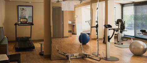 A gym with exercise equipment, a treadmill, and a large exercise ball.