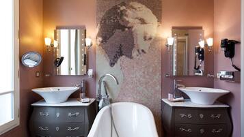 A bathroom with two sinks, a large bathtub, and a mosaic wall.