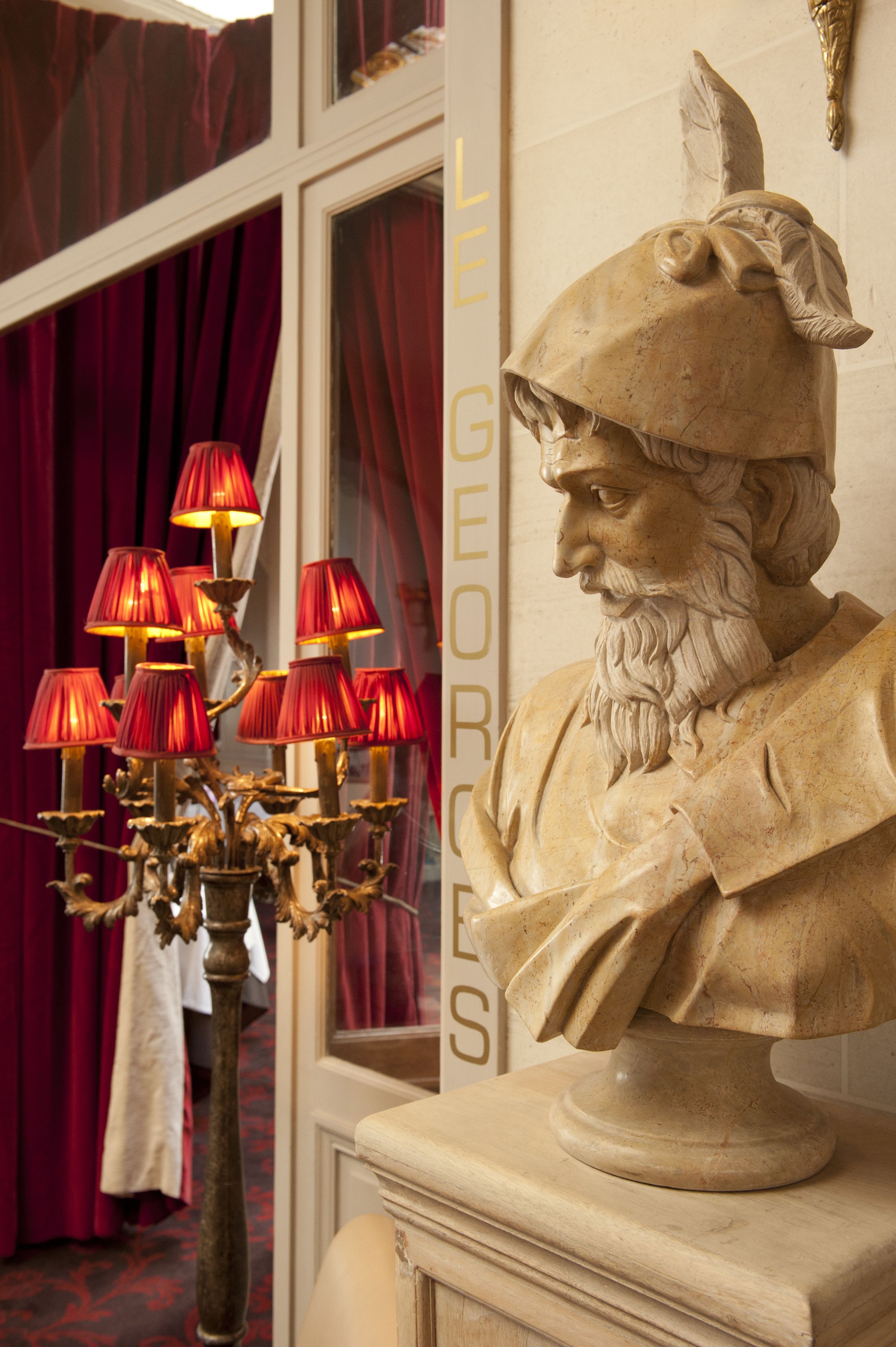 A bust of a historical figure with a decorative lamp in front of it.
