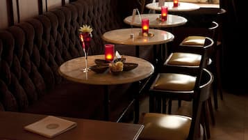A restaurant with round tables, cushioned booths, and candles.