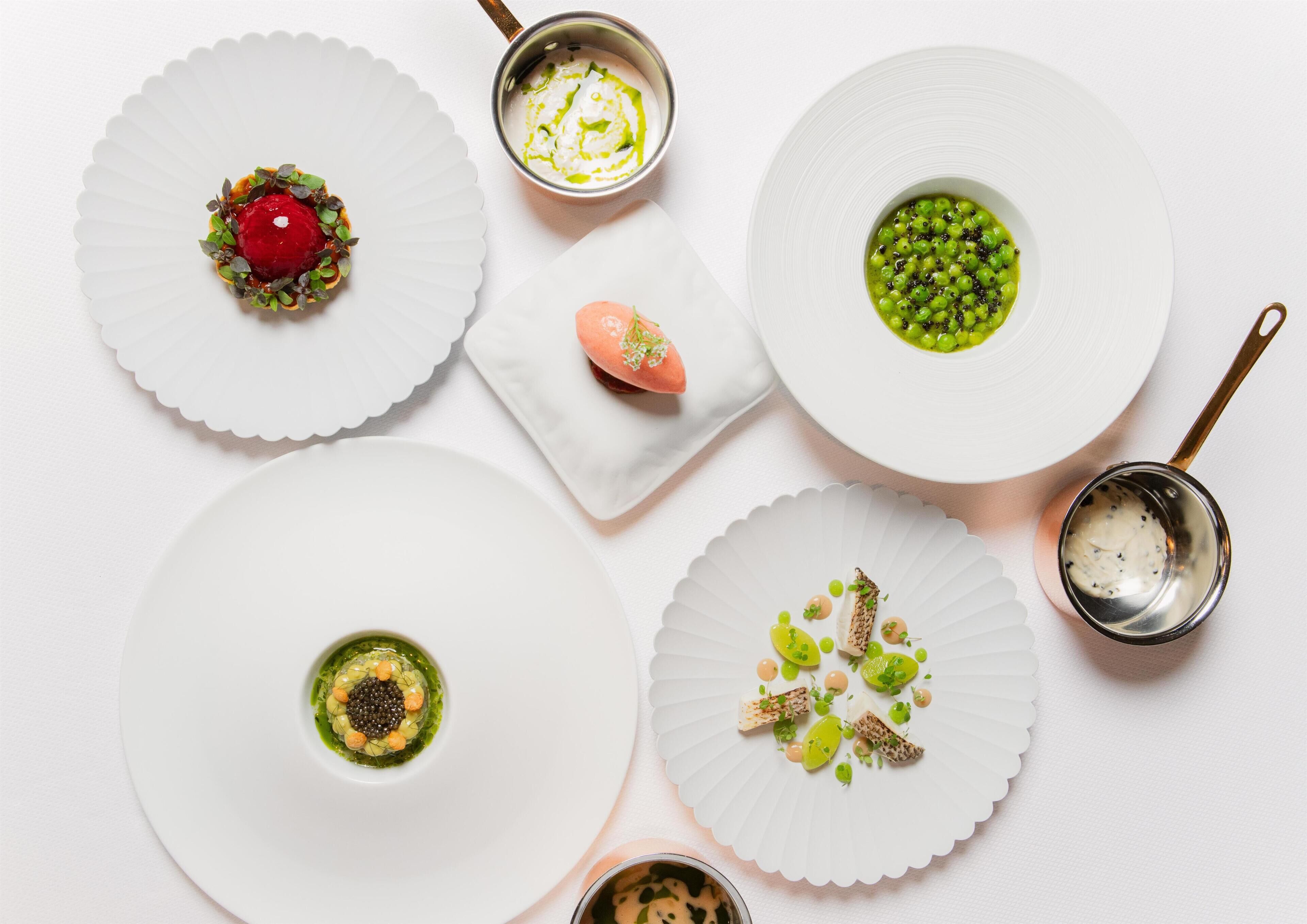 Vista cenital de una mesa con varios platos, cada uno en un plato blanco con borde festoneado.