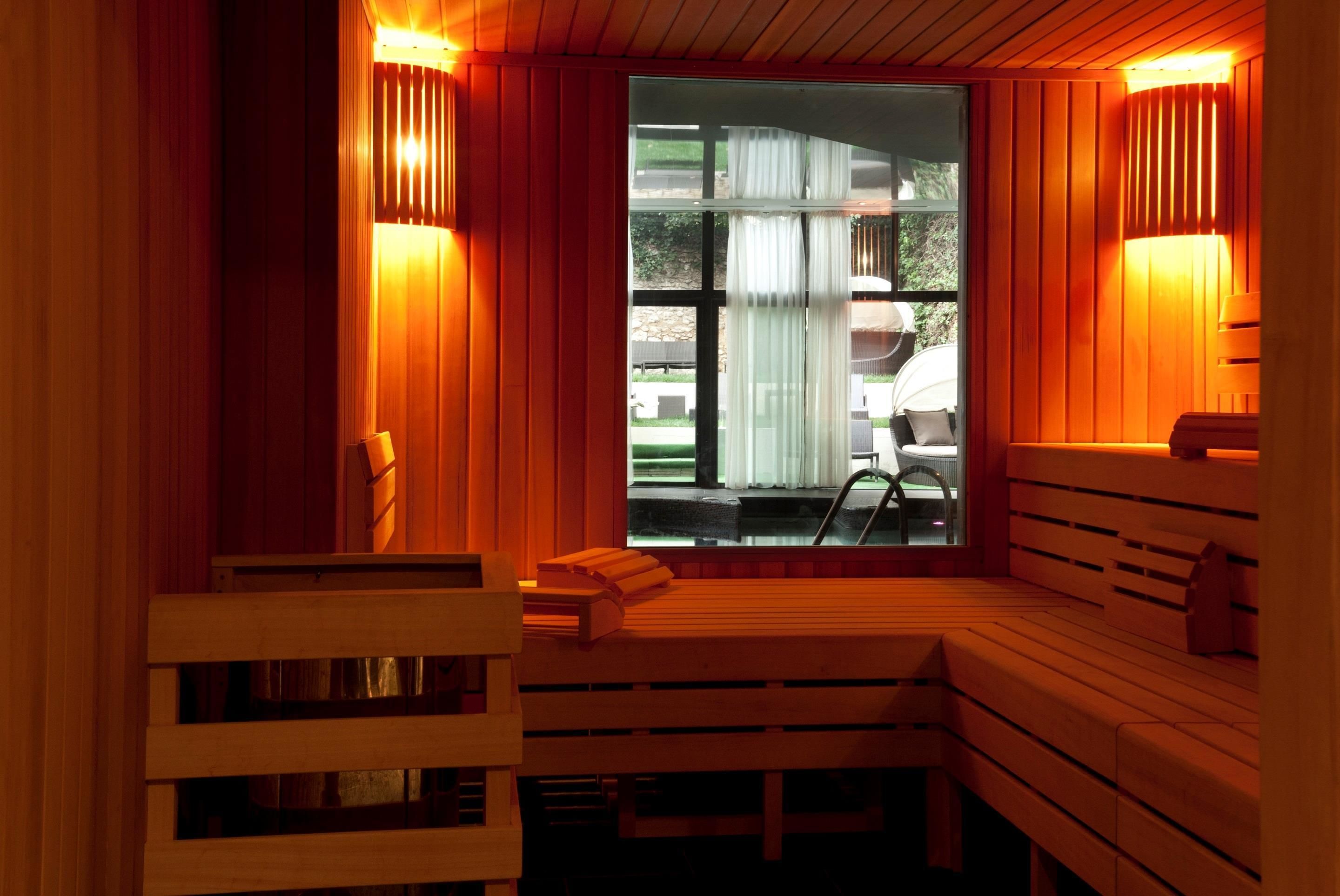 A sauna with wooden benches and a glass window, offering a view of the outdoors.