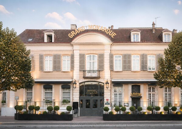 A hotel with a classic facade, a balcony, and a sign reading 'GRAND MONARQUE.'