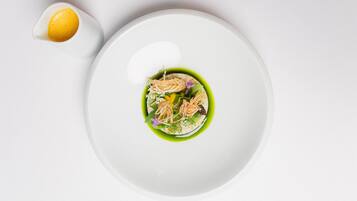 A white plate with a green sauce and seafood garnish.