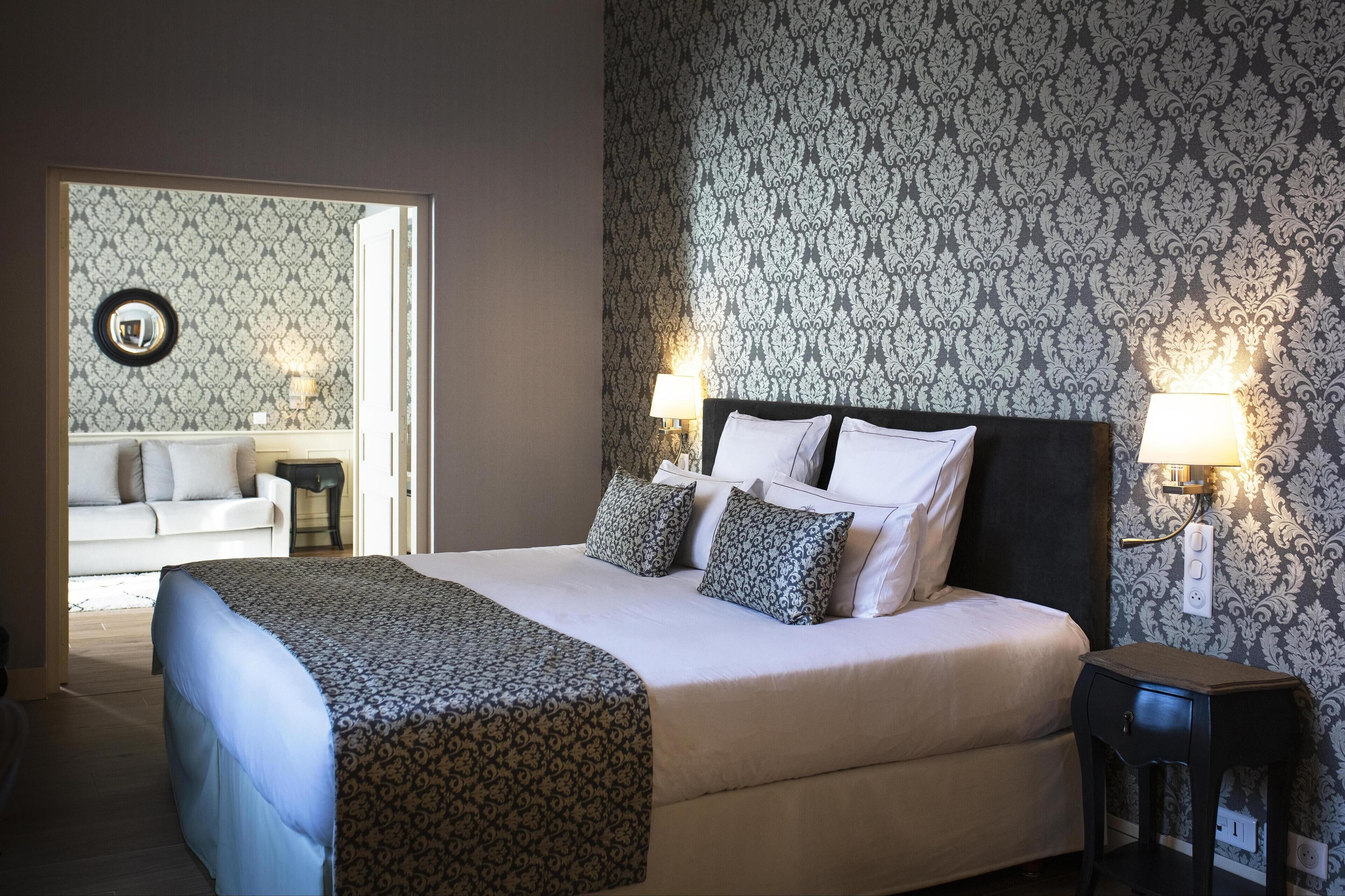 A hotel room with a large bed, two bedside lamps, a nightstand, and a mirror on the wall.