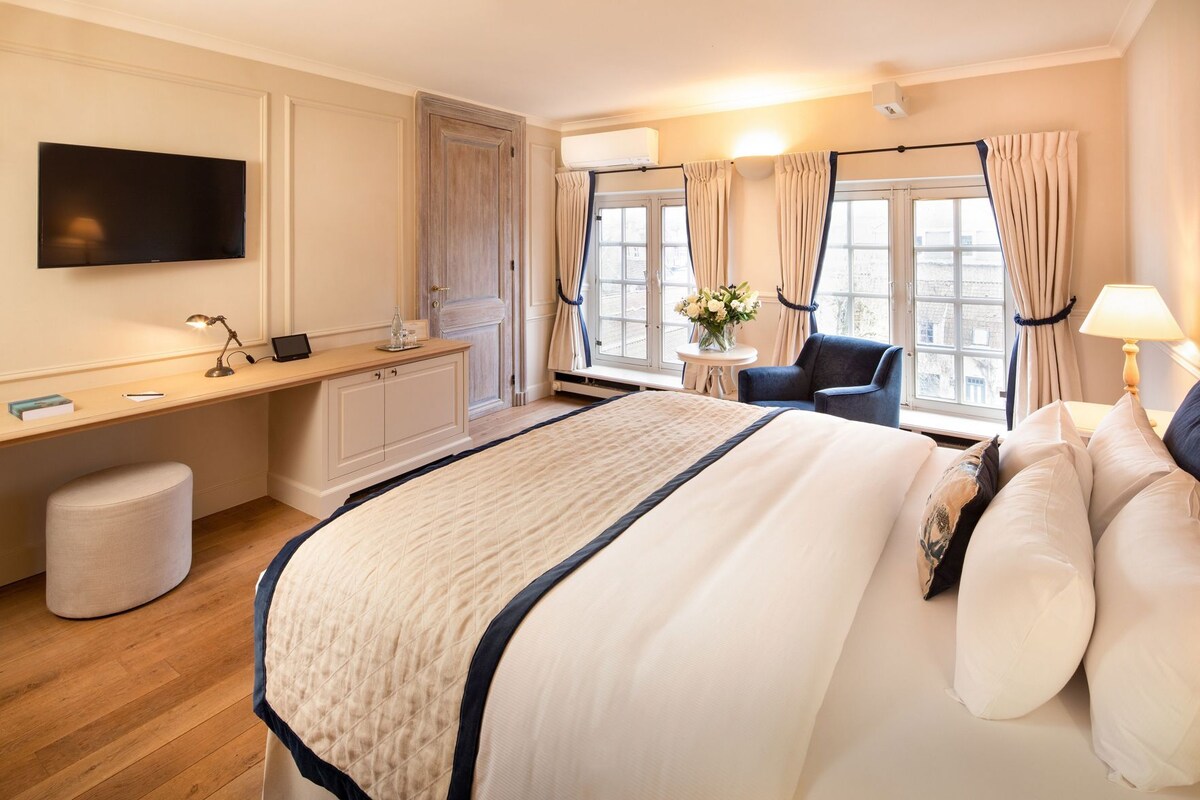 A hotel room with a bed, desk, chair, and a TV.