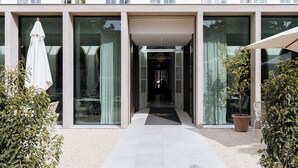 Un edificio moderno con un acceso cubierto, puertas de cristal y un camino que lleva al interior.