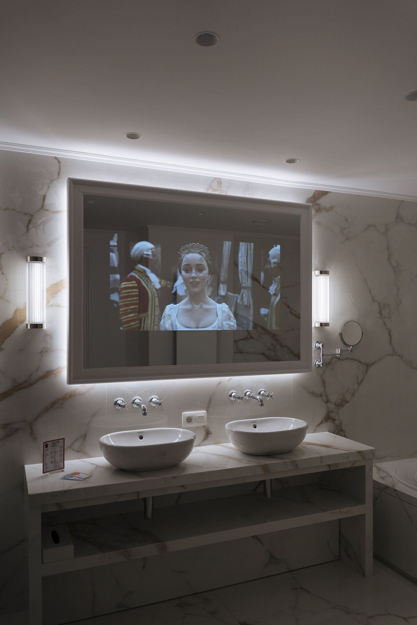 A bathroom with a large mirror, two sinks, and marble walls.