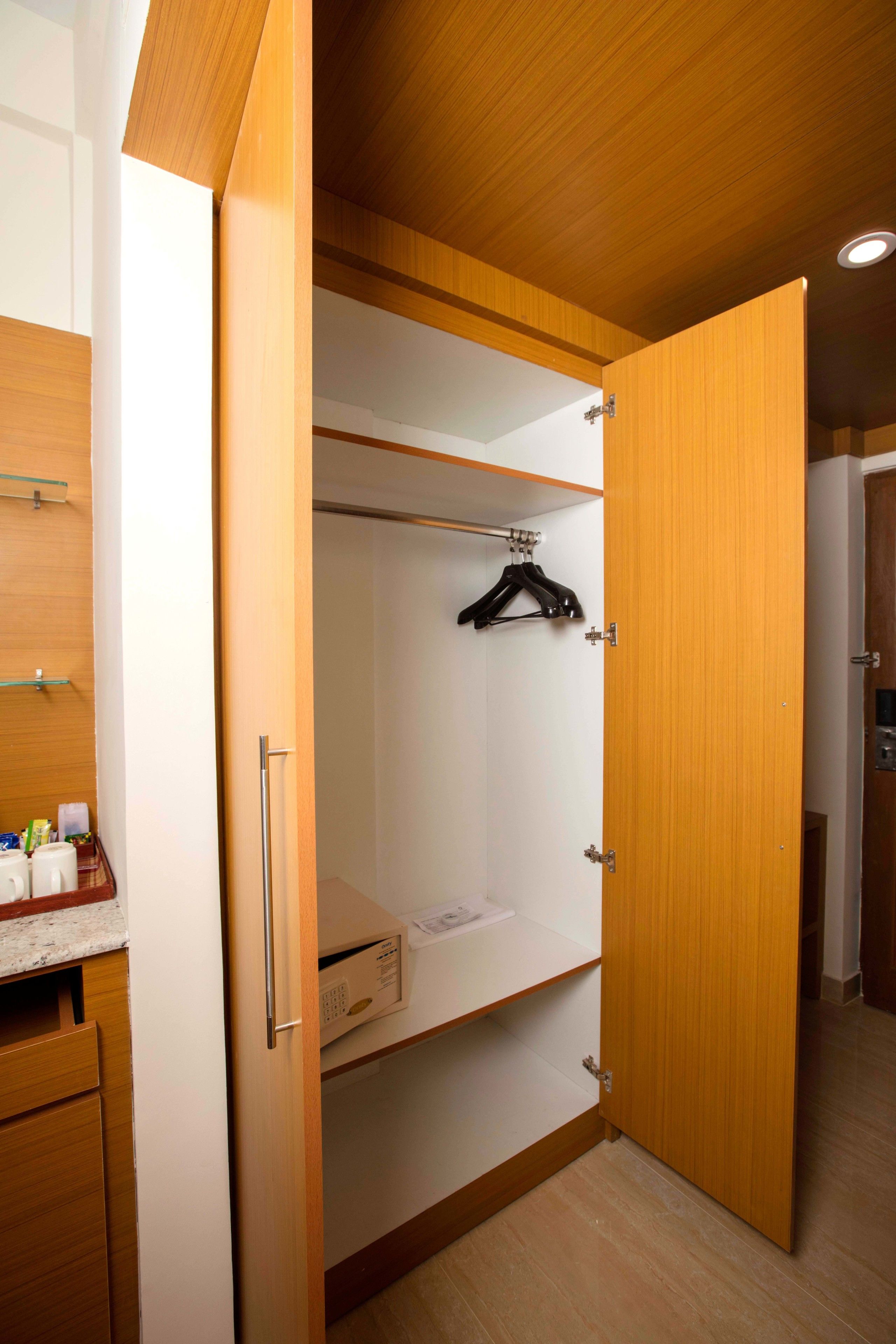 Un vestidor con puertas de madera, una barra para colgar ropa y un microondas en la encimera.