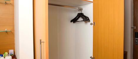 Un vestidor con puertas de madera, una barra para colgar ropa y un microondas en la encimera.