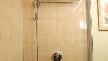 A shower with a towel rack, a showerhead, and a control knob.