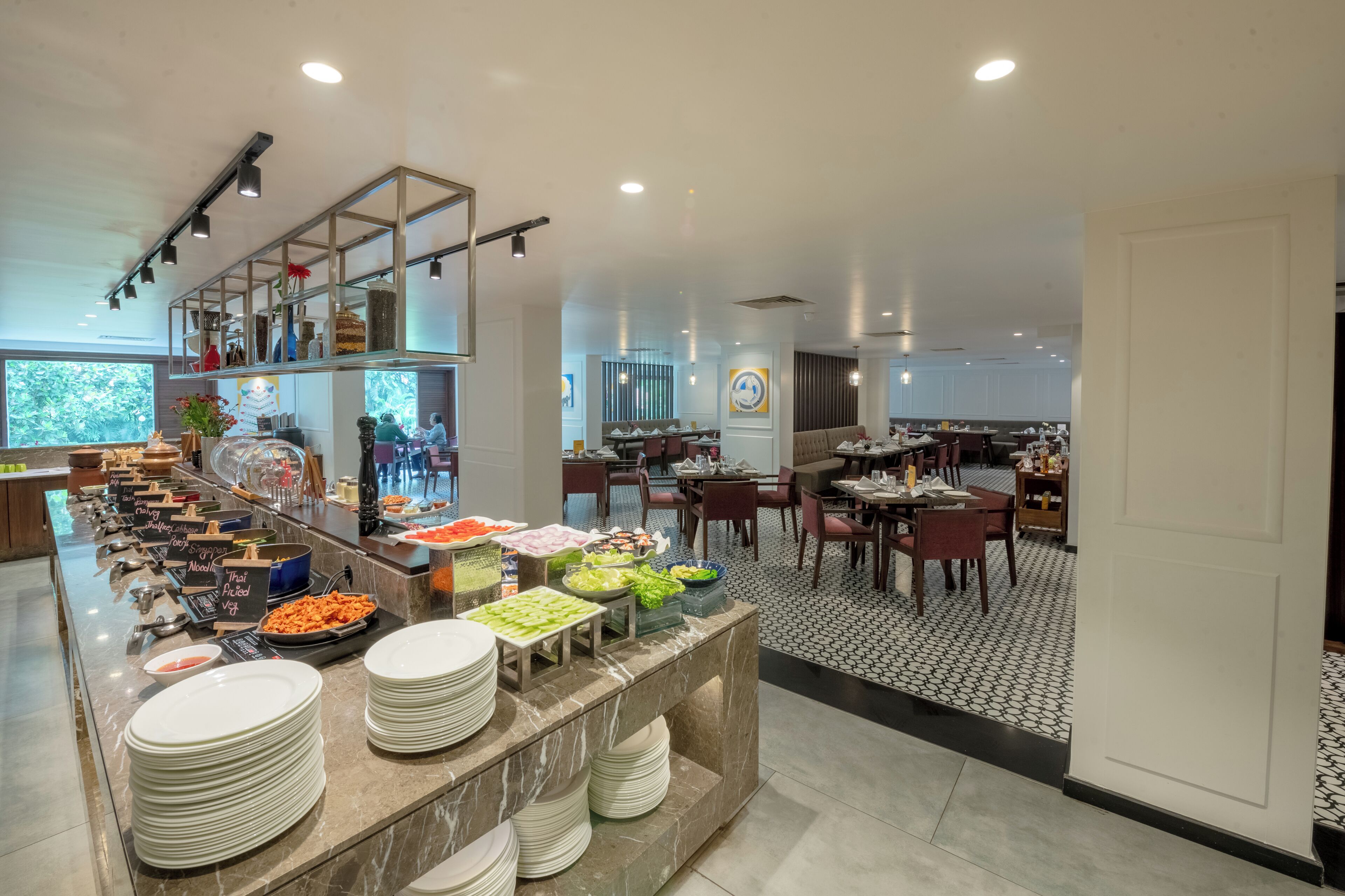 Un comedor de hotel moderno con mostradores de buffet, mesas y sillas.
