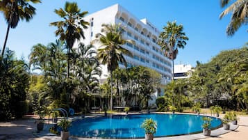 Un hotel con piscina rodeado de palmeras y plantas en macetas.