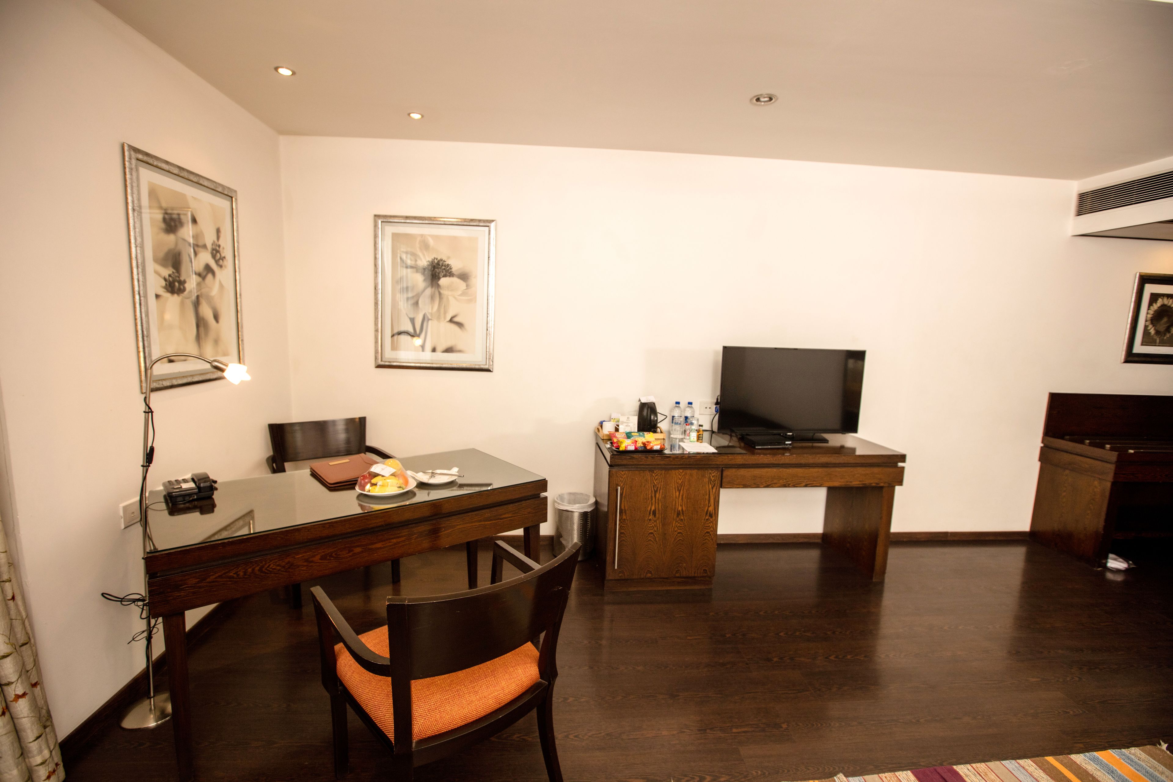 Una habitación de hotel con una mesa de comedor de madera, un televisor y un escritorio.