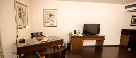 Una habitación de hotel con una mesa de comedor de madera, un televisor y un escritorio.