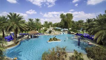 Una gran piscina al aire libre rodeada de palmeras y sillas de descanso azules.