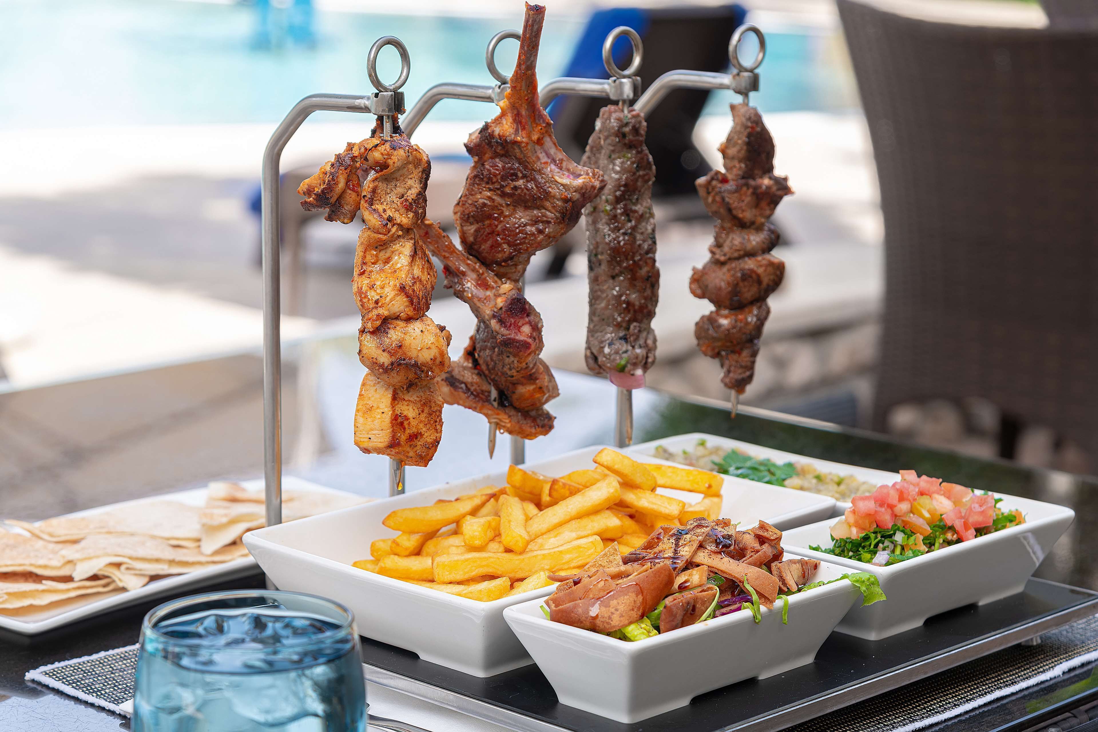 A buffet with grilled meats, French fries, salads, and flatbreads.