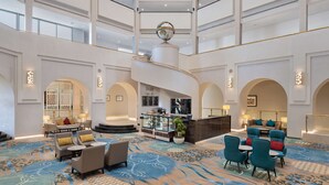 Eine großzügige Lobby mit einer zentralen Treppe, Sitzbereichen und einer Rezeption.