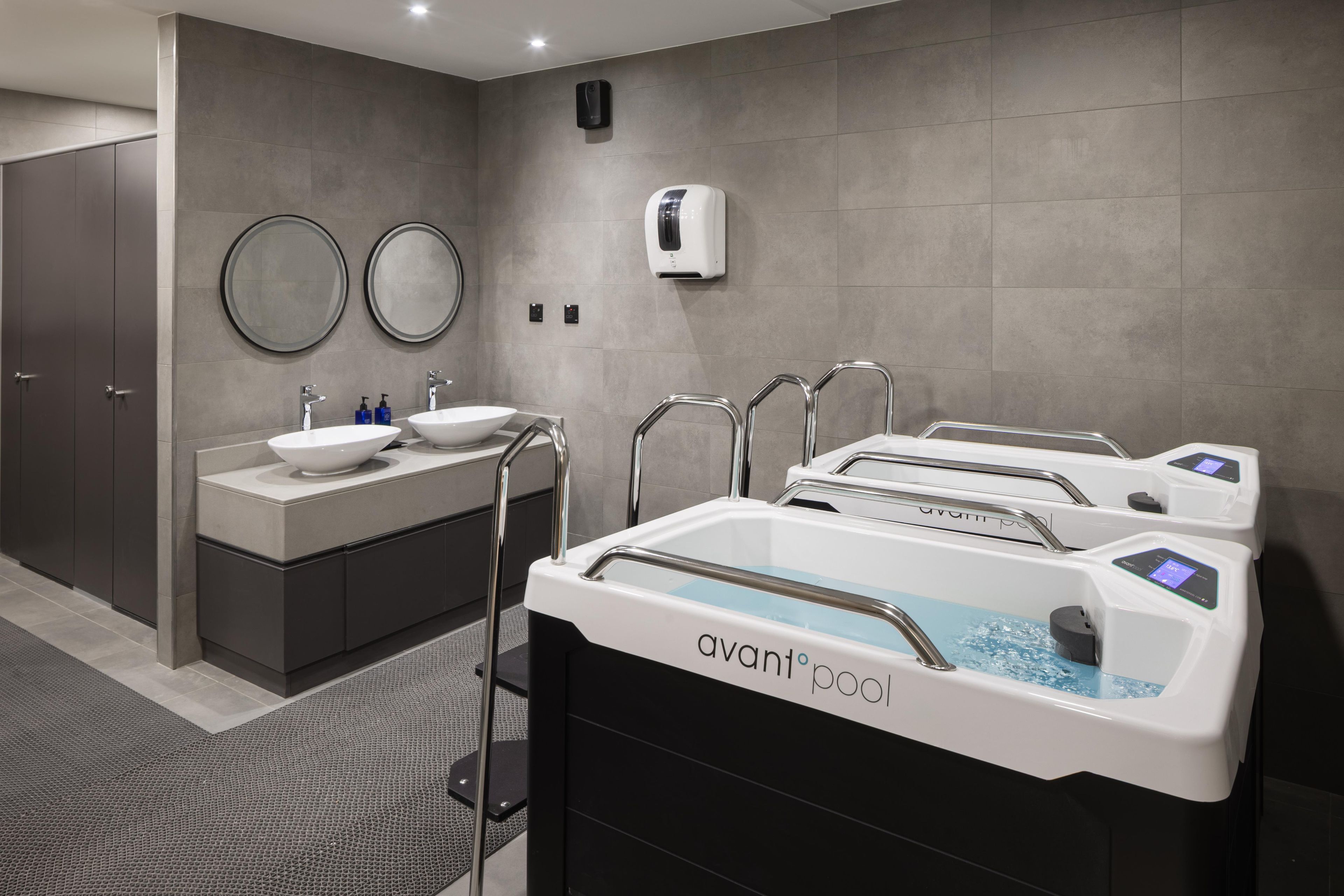 A modern bathroom with a vanity, two sinks, a large mirror, and a heated floor.