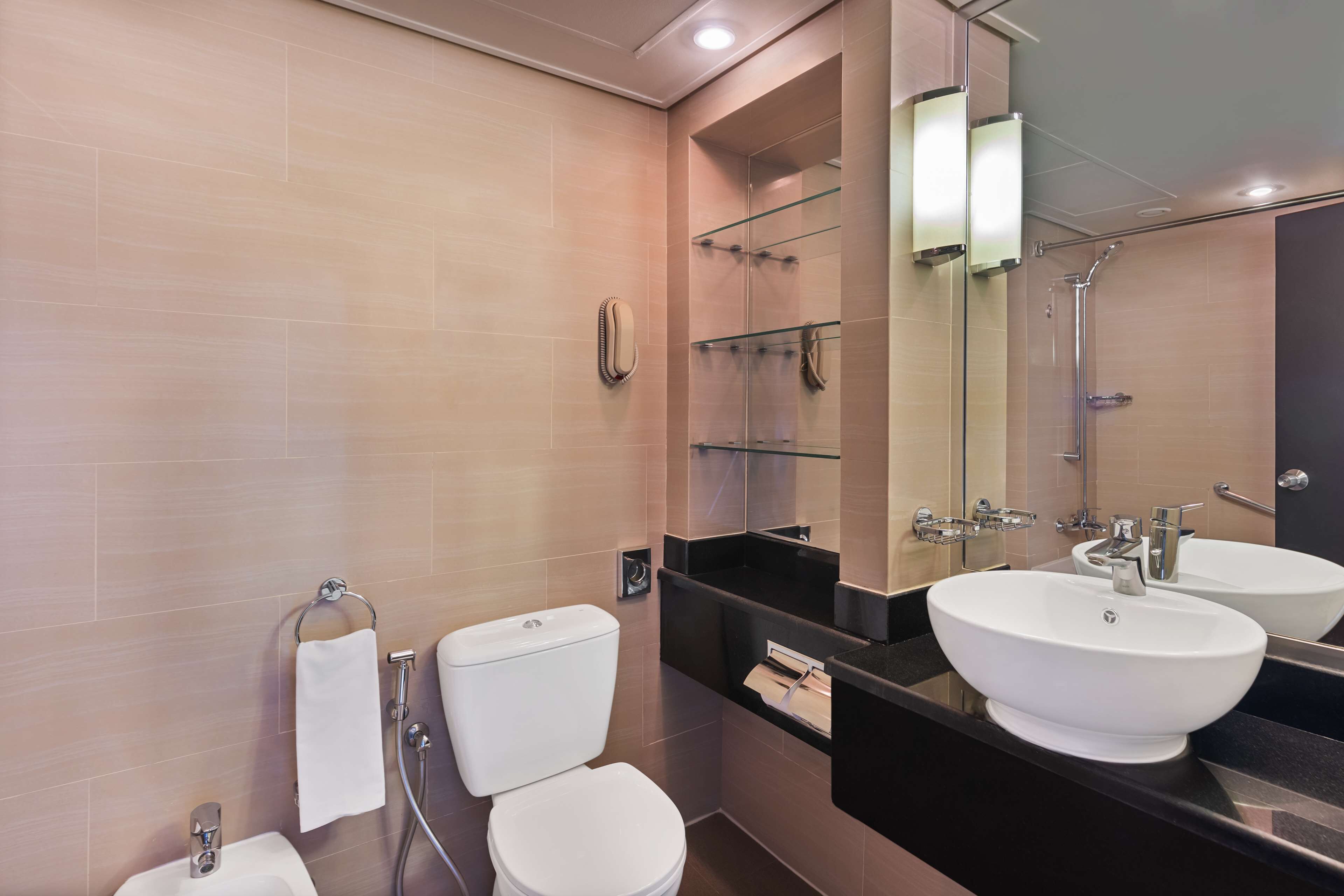 Een moderne badkamer met twee wasbakken, een toilet en een douche.