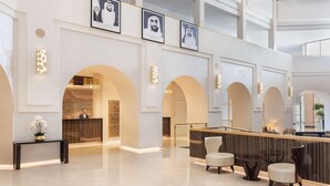 Eine großzügige Lobby mit Empfangsschalter, Sitzgelegenheiten und gerahmten Porträts an der Wand.