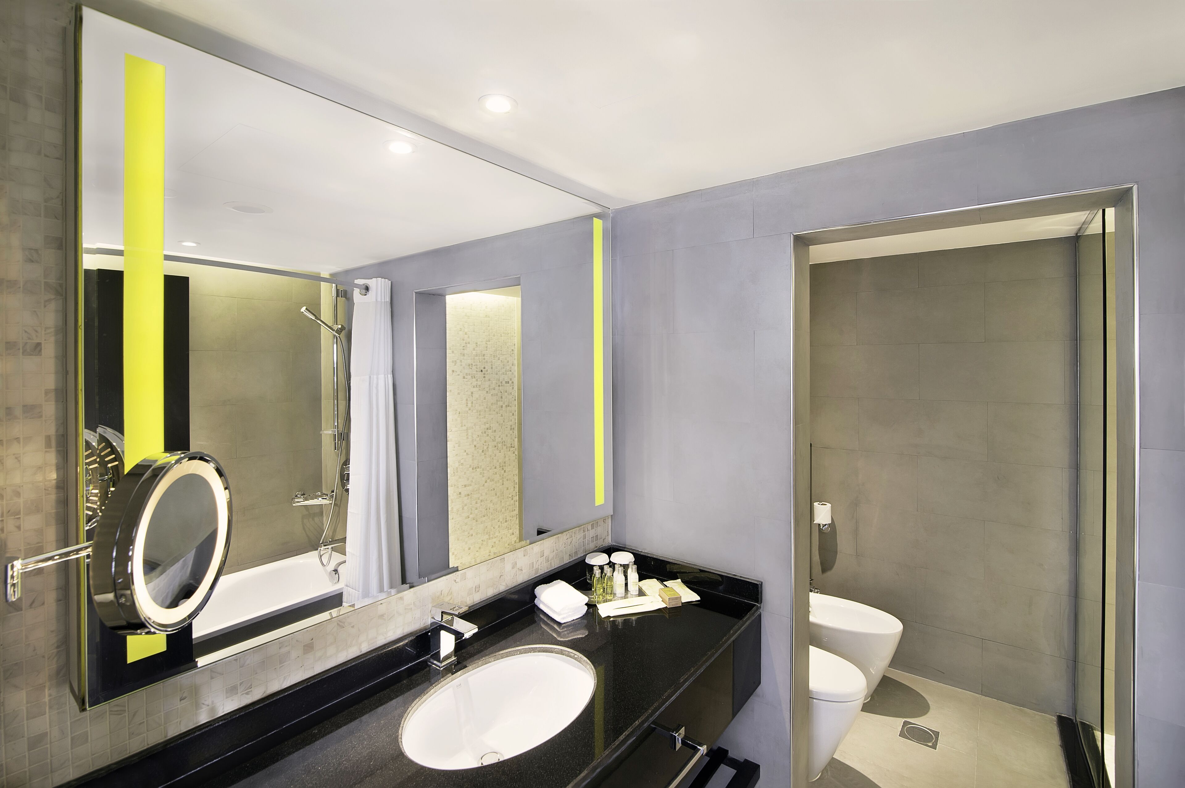 Een moderne badkamer met een grote spiegel, een badkuip, een toilet en een douche.
