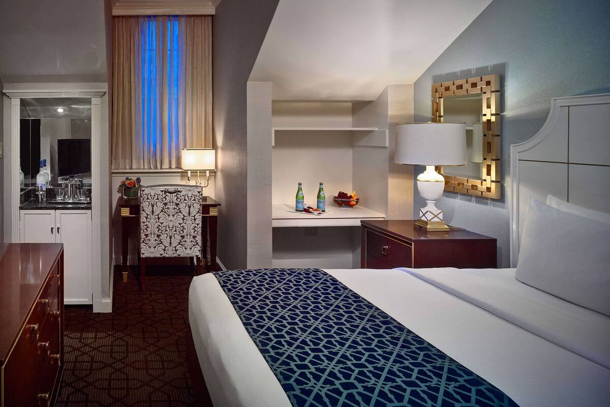 Ein Hotelzimmer mit Bett, Schreibtisch, Stuhl, Spiegel, Fernseher und Bad.