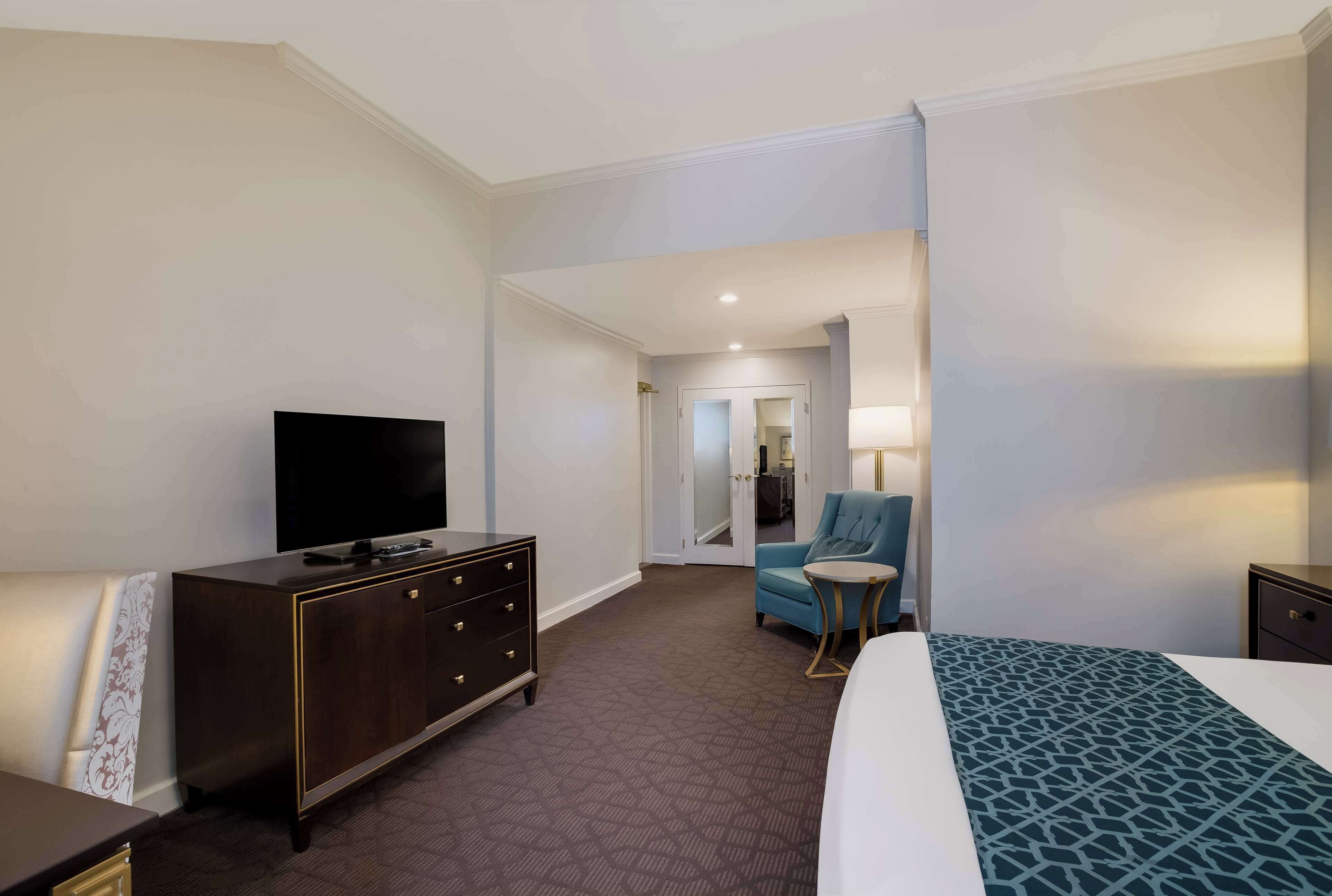Une chambre d’hôtel avec un lit, un téléviseur posé sur une commode, une chaise et une petite table.