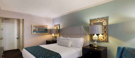 A hotel room with a bed, bedside tables, a chair, a painting, and a decorative wall piece.