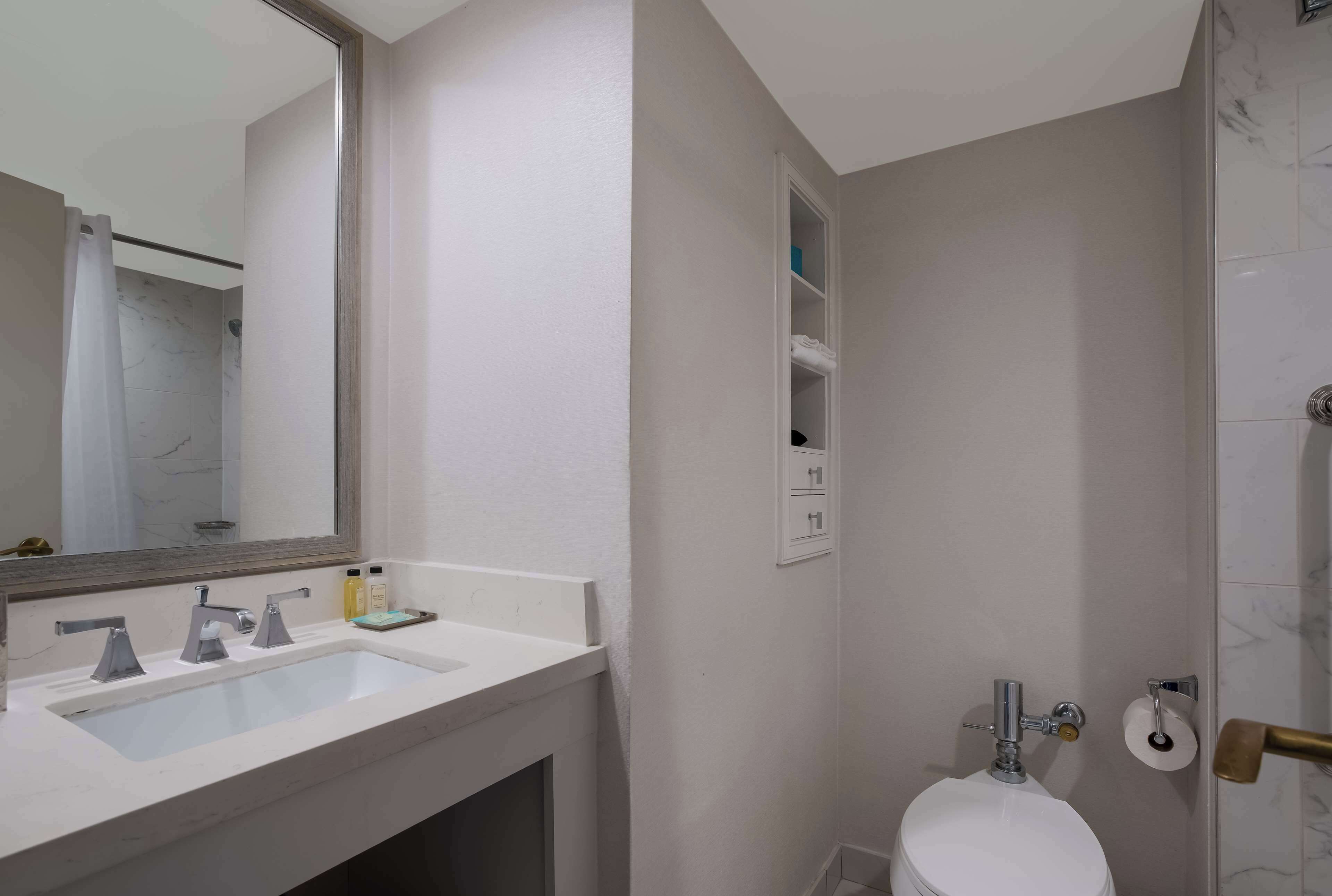 A bathroom with a white sink, mirror, and toilet.