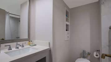 A bathroom with a white sink, mirror, and toilet.