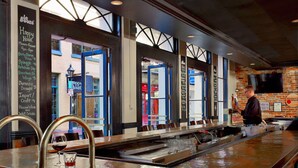 Eine Bar mit einer Kreidetafel, einem Barkeeper und Blick auf die Straße.