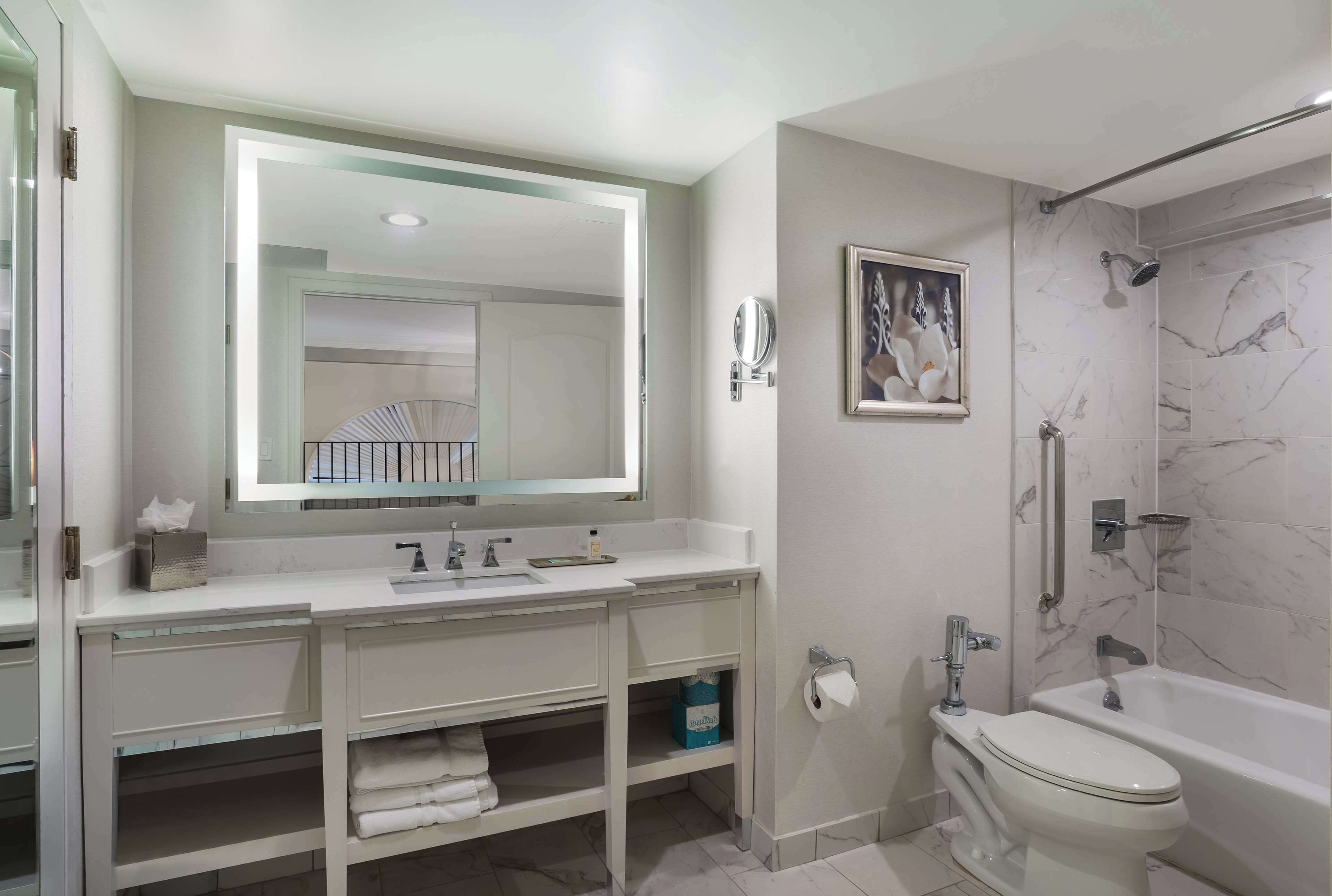 Un baño moderno con un espejo grande, una bañera, un inodoro y una ducha.