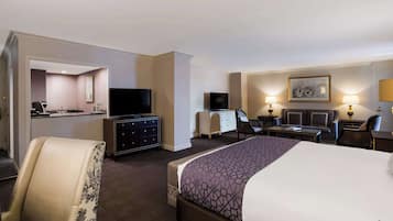 A hotel room with a bed, a desk, a chair, a television, and a desk with drawers.