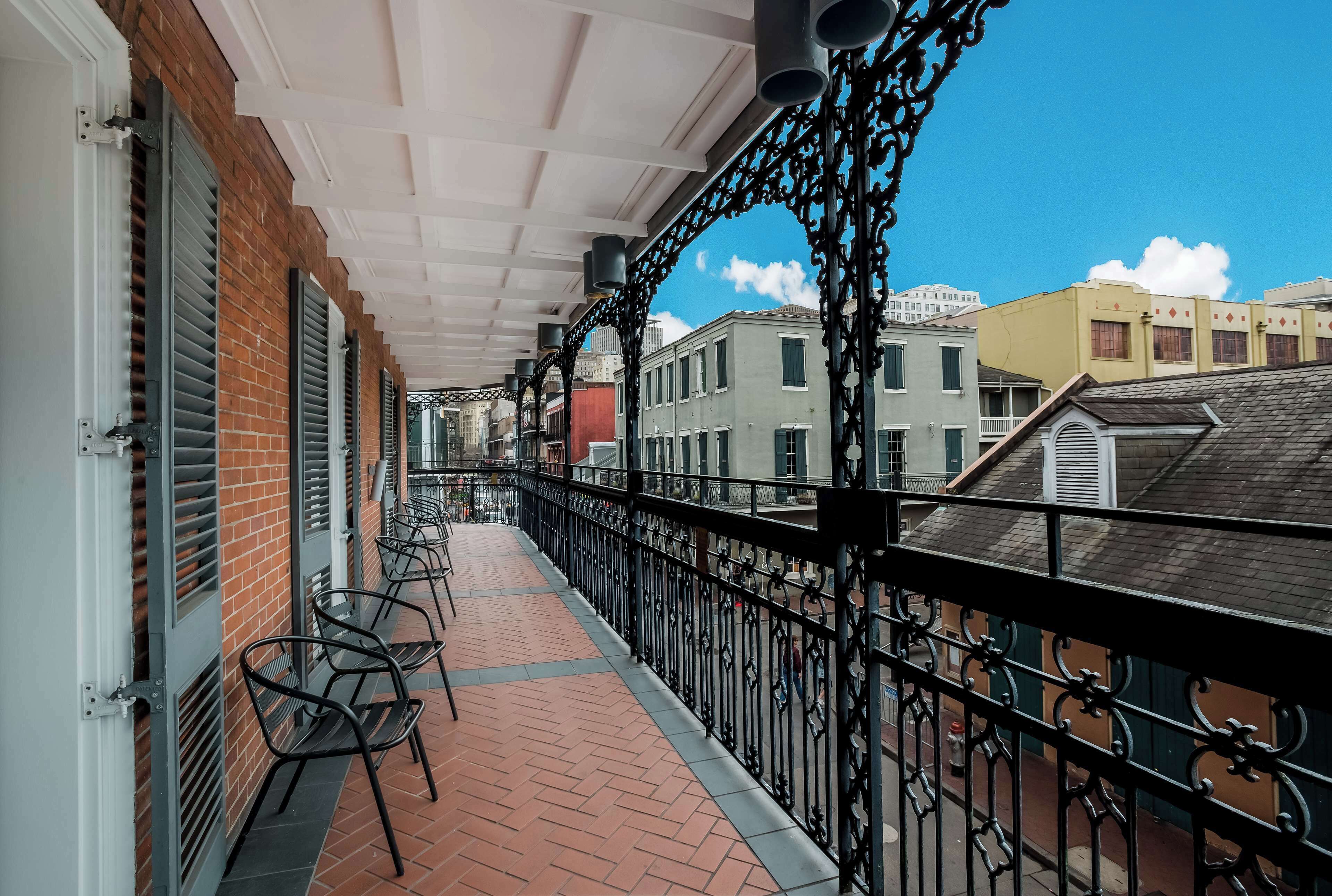 A balcony with metal railings, brick walls, and a tiled floor.
