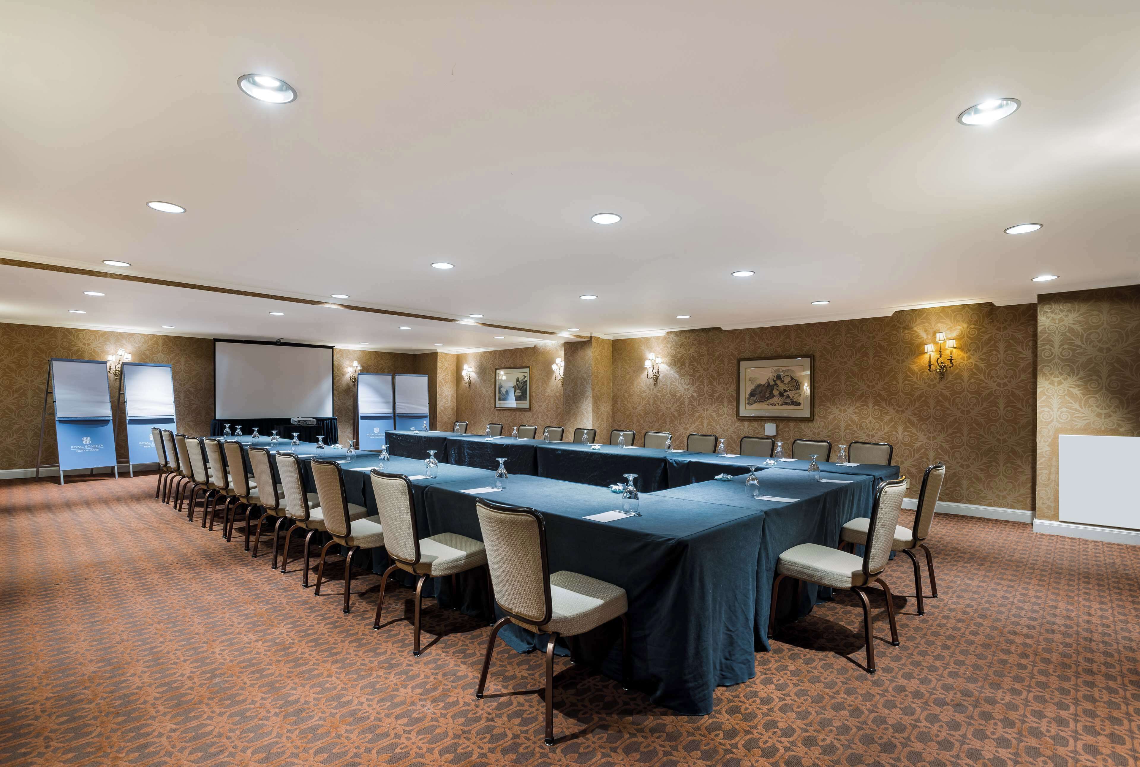 A conference room with a long table, chairs, and a projector screen.