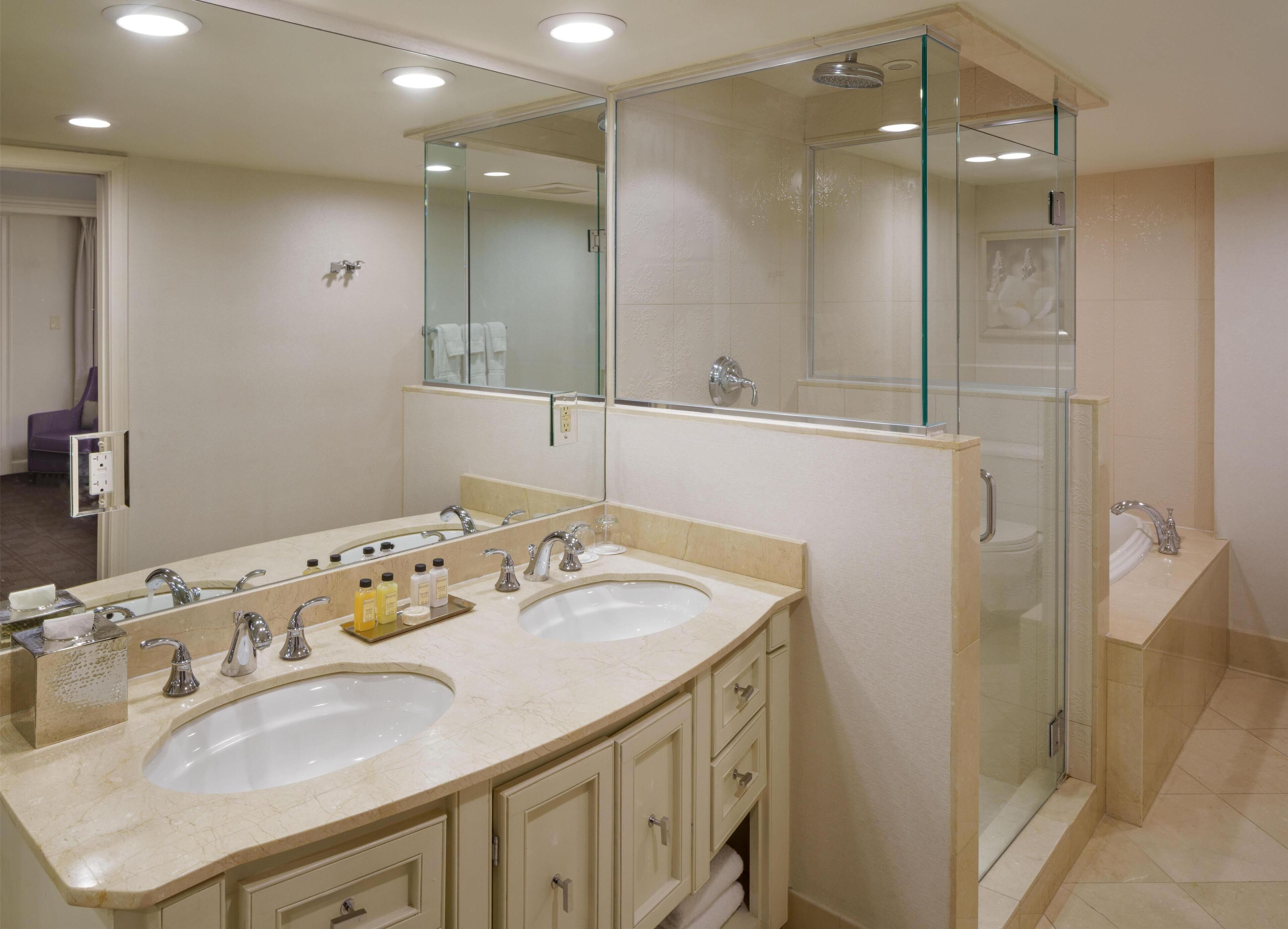 A bathroom with two sinks, a glass shower enclosure, and a large mirror.