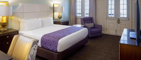 Una habitación de hotel con una cama grande, una silla, un escritorio y un televisor.