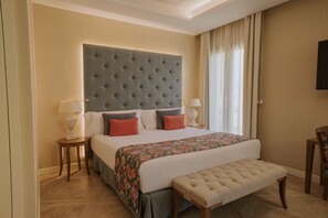Una habitación de hotel con una cama grande, dos mesitas de noche con lámparas, un banco y un televisor en la pared.