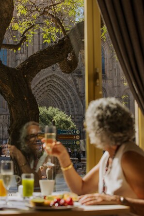 Uma área de refeições ao ar livre com vista para um edifício histórico com arcos e detalhada decoração em pedra.