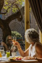 Uma área de refeições ao ar livre com vista para um edifício histórico com arcos e detalhada decoração em pedra.