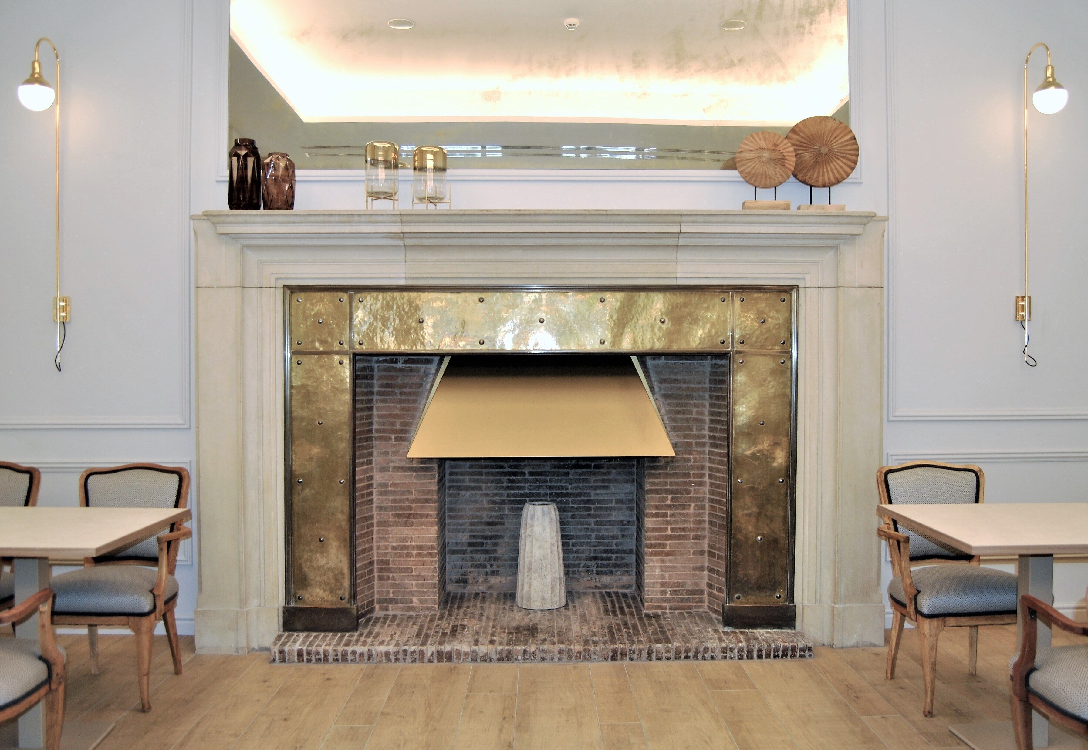 A fireplace with a brick facade and a gold-colored mantel, flanked by two wall-mounted lamps.