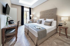 Habitación de hotel con una cama grande, un escritorio con silla, televisor y ventana con cortinas.